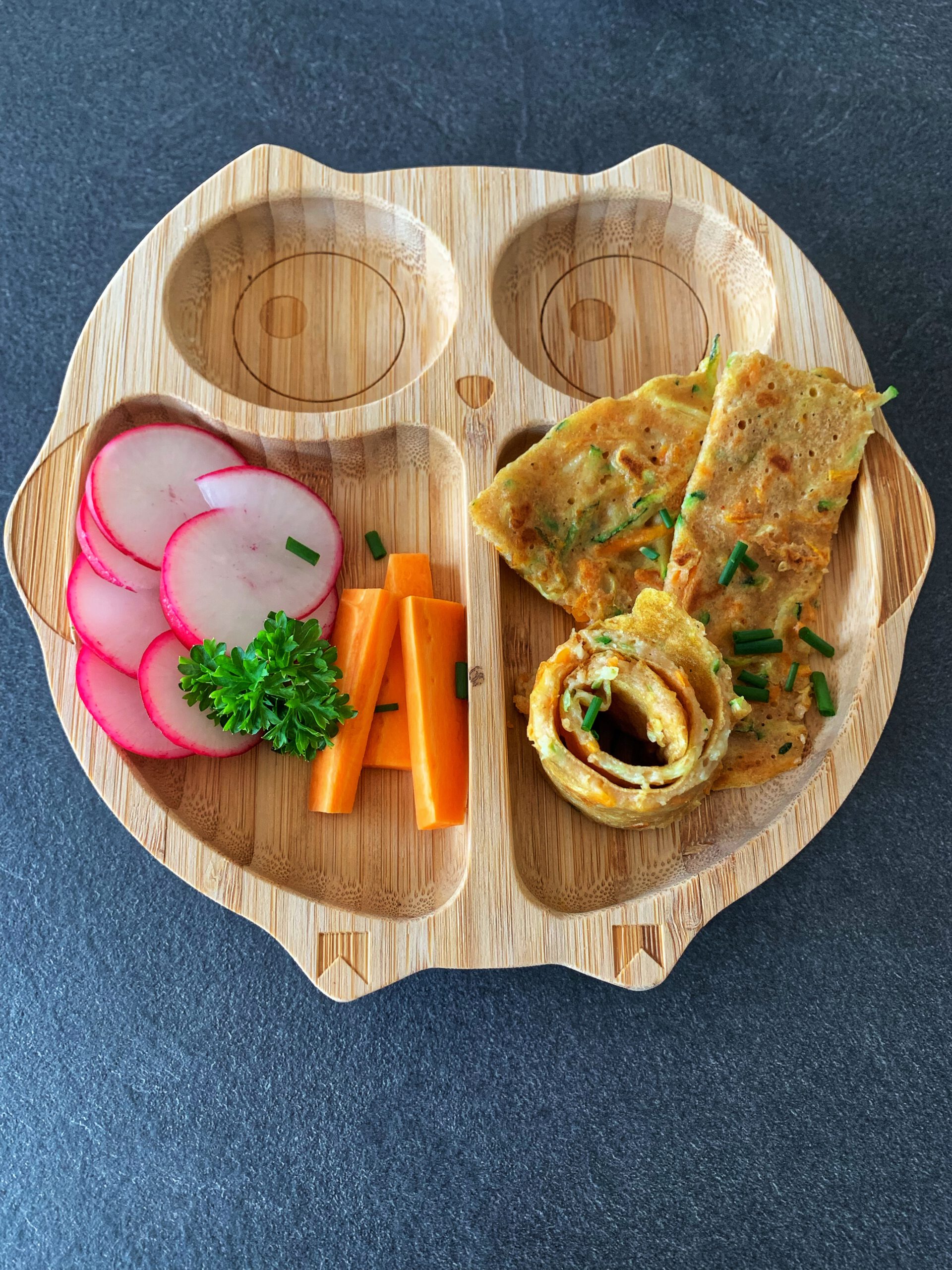 Gemüsepfannkuchen auf einem Kinderteller zusammen mit Radieschen und Karotte. Schnelles und gesundes Rezept für Kinder