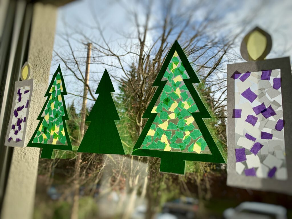 Bunte Fensterbilder in Form von Tannenbäumen und Kerze an einem Fenster. Gebastelt mit Kleinkind und aus einfachen Materialien wie Tonpapier, Klebefolie und Transparentpapierschnipseln. Bastelidee für Kinder unter 3 zu Weihnachten.  