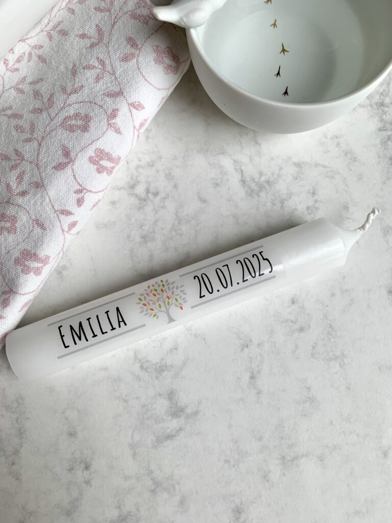 Gastgeschenk Taufe Kerze personalisieren mit Kerzentattoo Bild: Fertige DIY Gastgeschenk Taufe Mini Stabkerzen mit personalisiertem Namen und Datum. Im Hintergrund sieht man ein Schälchen mit Wasser und ein Handtuch. Beides wird zum Aufbringen des Kerzentattoos benötigt.