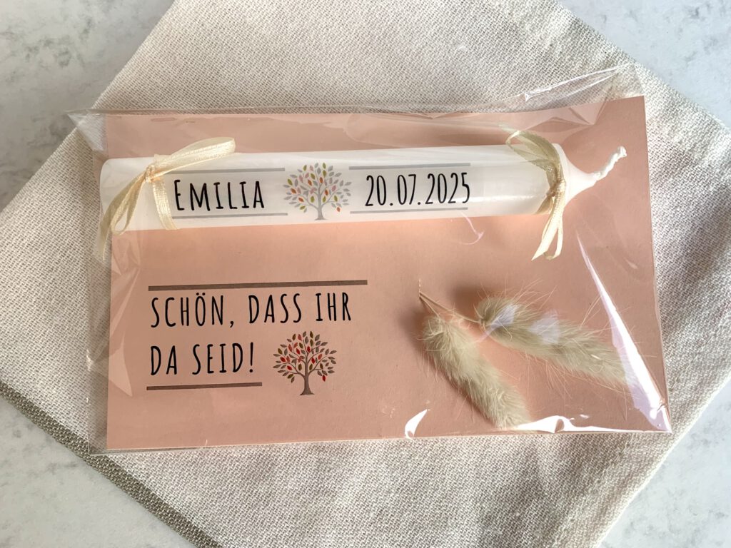 Gastgeschenke-Taufe-Kerze-verpackt Einfaches DIY Gastgeschenk für die Taufe: Kleine Stabkerze mit Hilfe von Transferfolie mit dem Namen des Taufkindes und dem Taufdatum bedruckt. Mit einem Lebensbaum als Motiv versehen. Auf farbigem Karton mit kleinen Schleifen befestigt und mit dem Schriftzug "Schön, dass du da bist" versehen. Dekoriert mit Trockenblumen. Verpackt in Cellophan. Von oben fotografiert.