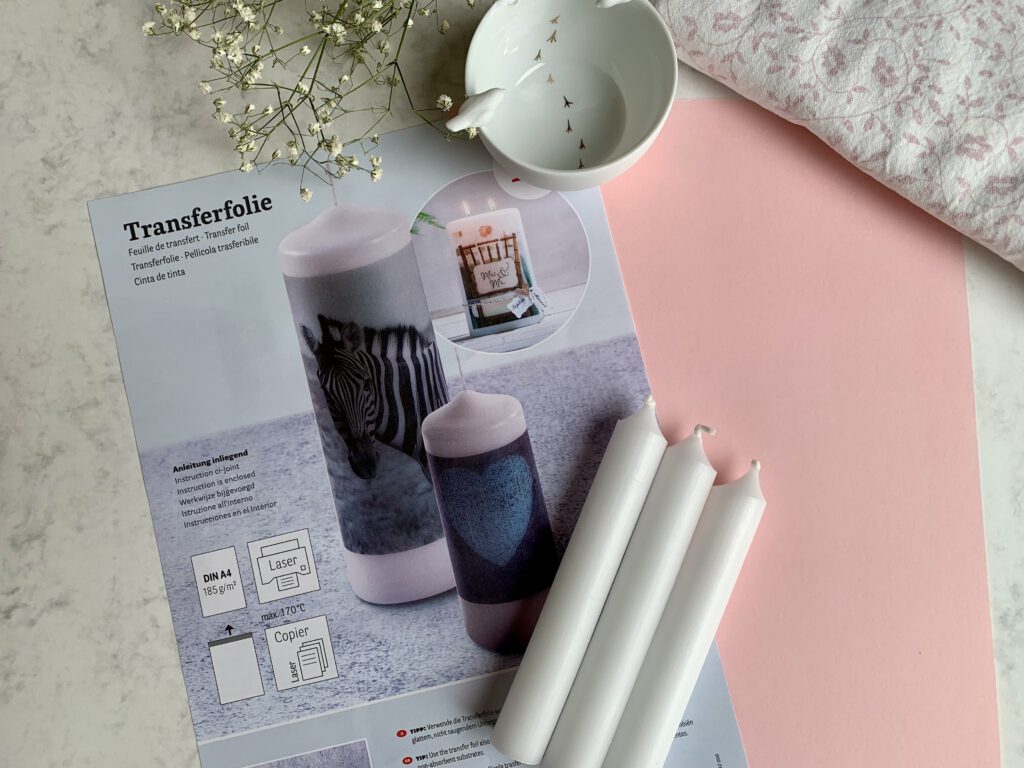 Gastgeschenke Taufe selber machen Material für personalisierte Kerzentattoos Foto der Materialien für die Anleitung 'DIY Gastgeschenke zur Taufe': Kerzen, Wasserschiebefolie, Papier, Schälchen mit Wasser und Handtuch