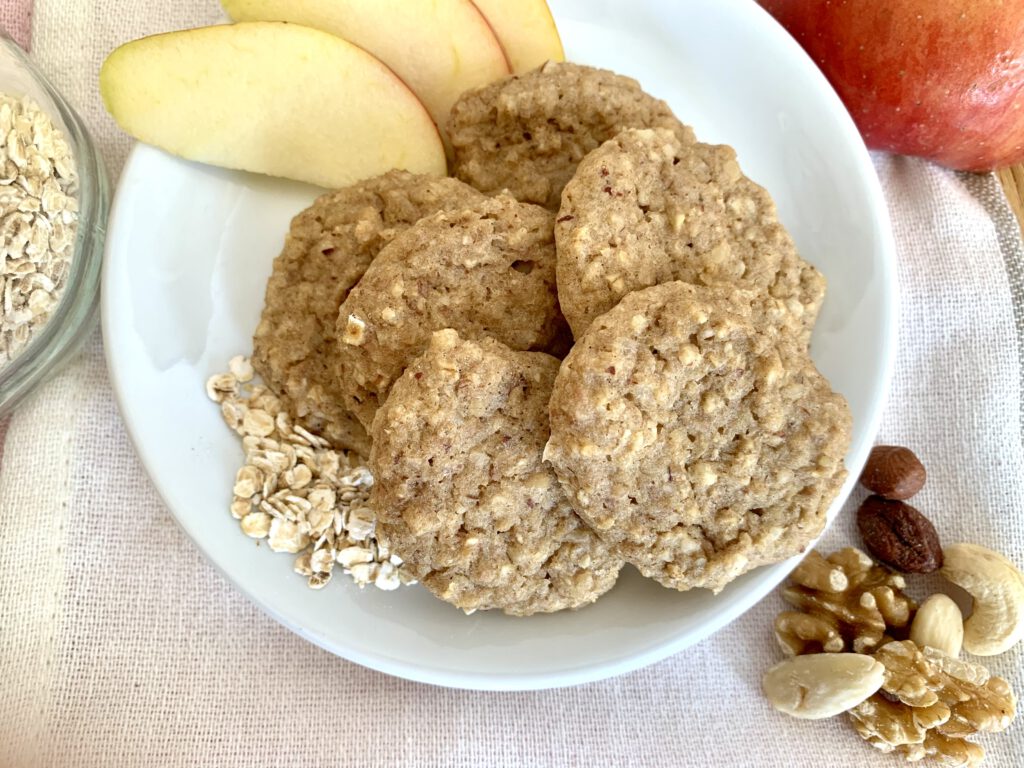 apfelmus-haferflocken-kekse-teller Apfelmus Kekse ohne Zucker auf einem Teller, serviert mit Apfelspalten und Nüssen - ideal als gesunder Snack oder für die Brotdose