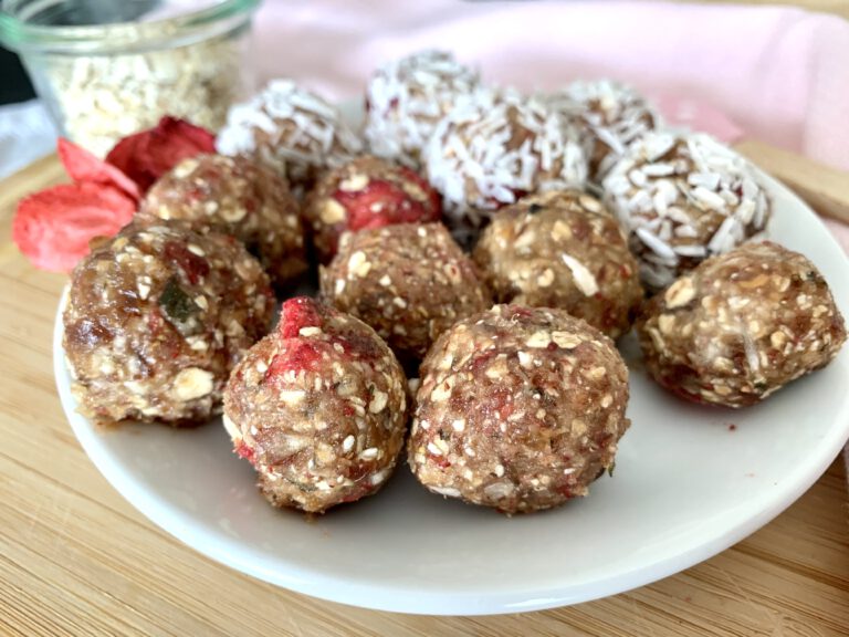 Selbstgemachte Erdbeer Bliss Balls, teils natur, teils mit Kokosraspeln – gesunder und zuckerfreier Snack.