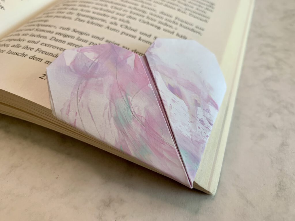 IMG_E3218 Herzförmiges Lesezeichen aus Kinderzeichnung liegt in einem aufgeklappten Buch - liebevolle DIY Geschenkidee mit Kleinkind