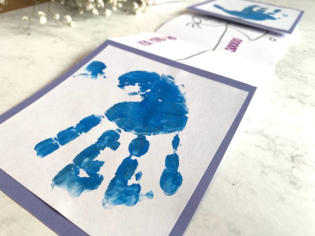 Süße Idee zum Vatertag: Wir basteln eine Klappkarte mit Handabdrücken. Auch für Babys geeignet. Auf der Außenseite zwei blaue Handabdrücke, im Inneren eine Überraschung für Papa. Ideale Geschenkidee zum Vatertag.