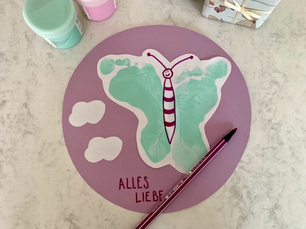 geburtstagskarte-fuer-oma karte basteln mit fußabdruck kleinkind: Selbstgebastelte Schmetterlingskarte mit Fußabdrücken und Schriftzug „Alles Gute“
