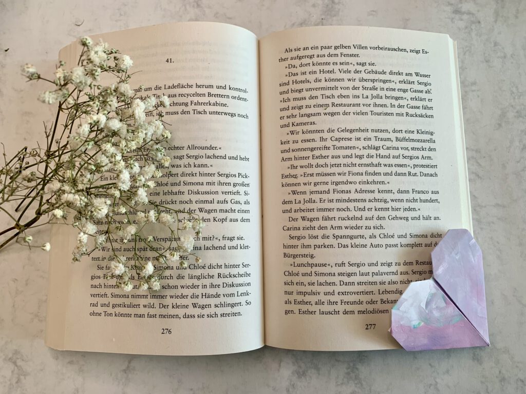 geschenk-basteln-mit-kind Aufgeschlagenes Buch mit Lesezeichen gebastelt aus Kinderkunst, daneben Schleierkraut