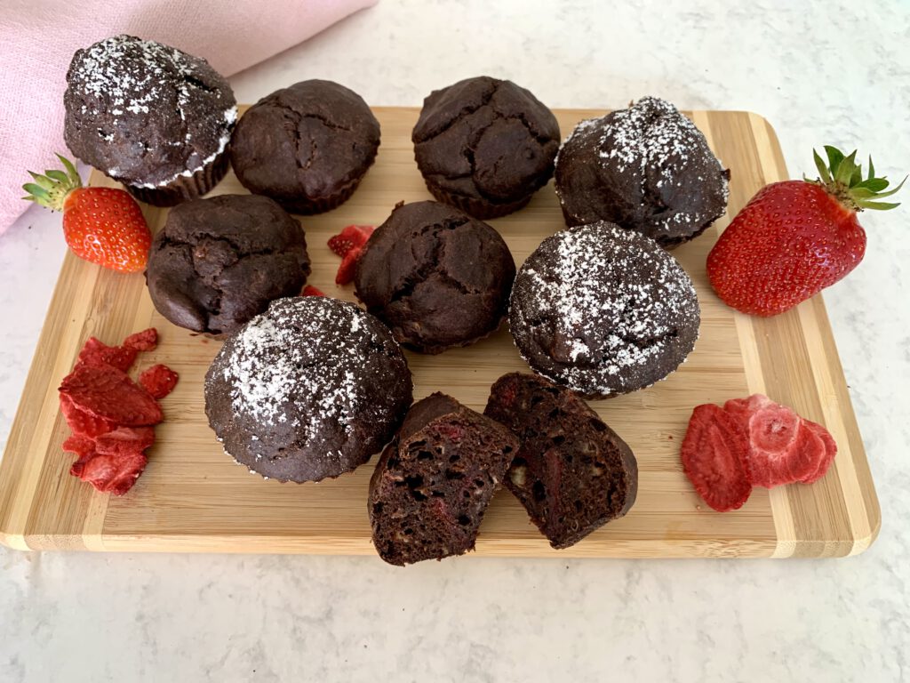 zuckerfreie-schokimuffins-holzbrett-erdbeeren Mehrere zuckerfreie Schokomuffins auf einem rustikalen Holzbrett, dekoriert mit frischen Erdbeeren – ideal für Kindergeburtstage