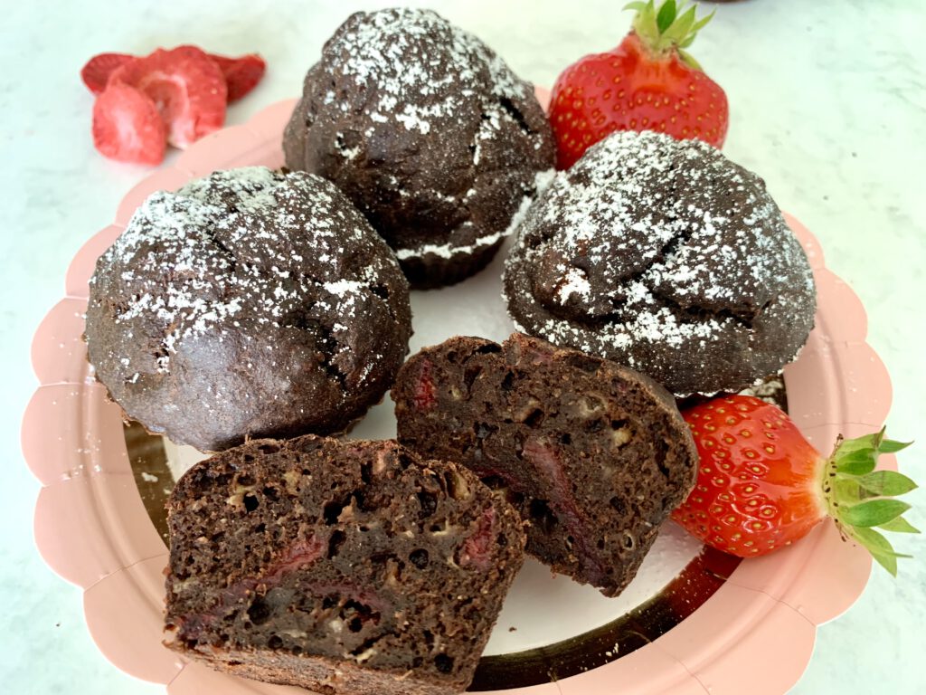 zuckerfreie-schokomuffins-aufgeschnitten Vier zuckerfreie Schokonmuffins dekorativ auf einem Teller angerichtet, mit frischen Erdbeeren, ideal zum Mitbringen für das Kuchenbuffet in der Kita