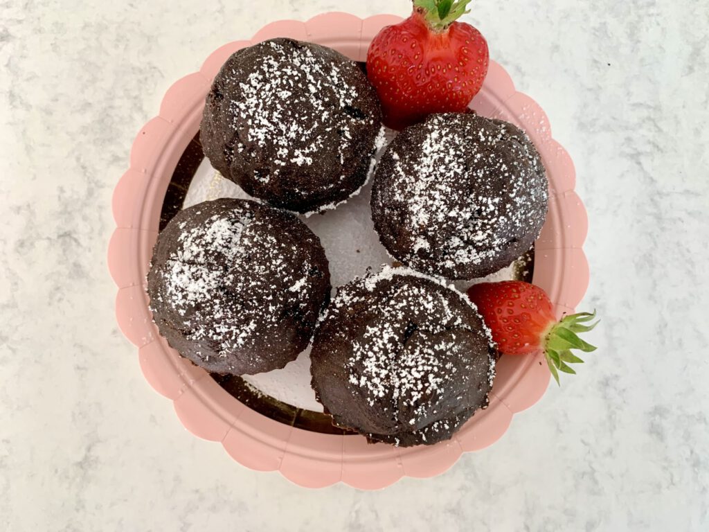 zuckerfreie-schokomuffins-mit-erdbeeren-von-oben Vier zuckerfreie Schokomuffins dekorativ auf einem Teller angerichtet, mit frischen Erdbeeren