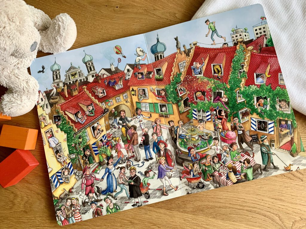 wimmelbuch-augsburg-fuggerei-szene.jpg Detailreiche Illustration der Augsburger Fuggerei mit Jakob Fugger, Brecht, Schubkarrenrennen und Kasperle im Buch "Das große Augsburger Wimmelbuch".
