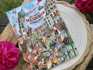 Cover des großen Augsburger Wimmelbuchs mit bunten Szenen aus der Stadt und Kasperle in der Mitte.