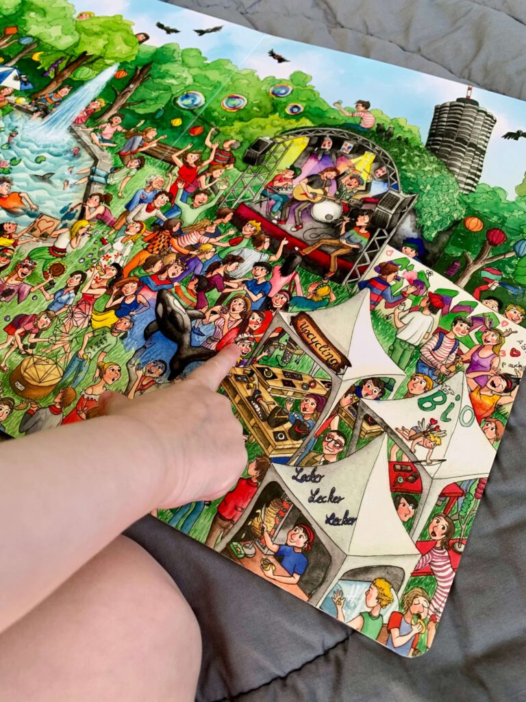 kind-wimmelbuch-hand.jpg Kleinkind zeigt mit dem Finger auf Kasperle auf dem Modular Festival des Augsburger Wimmelbuchs.
