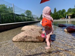 Kleinkind planscht im flachen Wasser des Lechtalbads – naturnahes Freibad in Kaufering bei Augsburg
