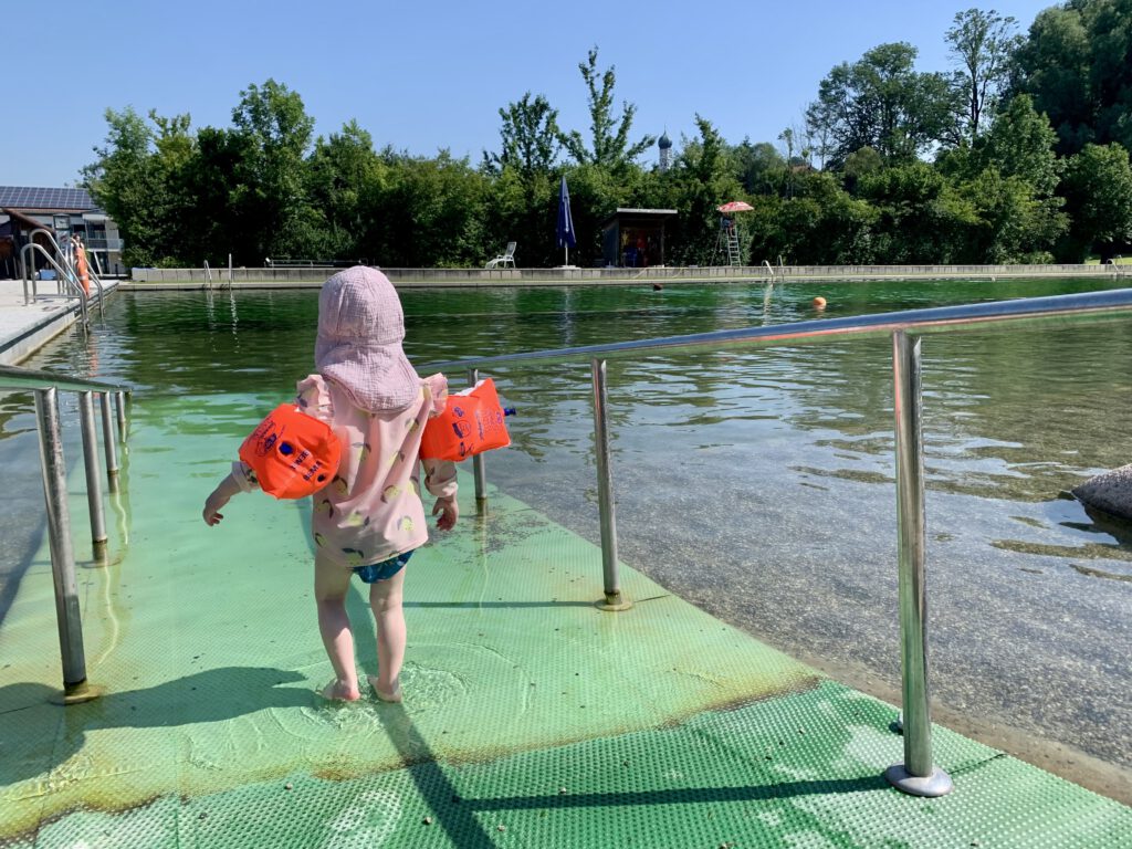kleinkind-geht-ins-wasser-naturfreibad.jpg Kleinkind läuft ins klare Wasser des Naturfreibads Lechtalbad – sanfter Einstieg für Kinder