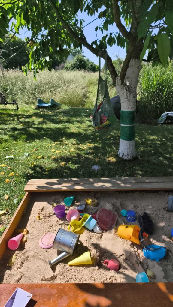 sandkasten-kaufen.jpg Einfacher Holzsandkasten mit Sandspielzeug. Sandkasten für Kleinkinder im Garten.