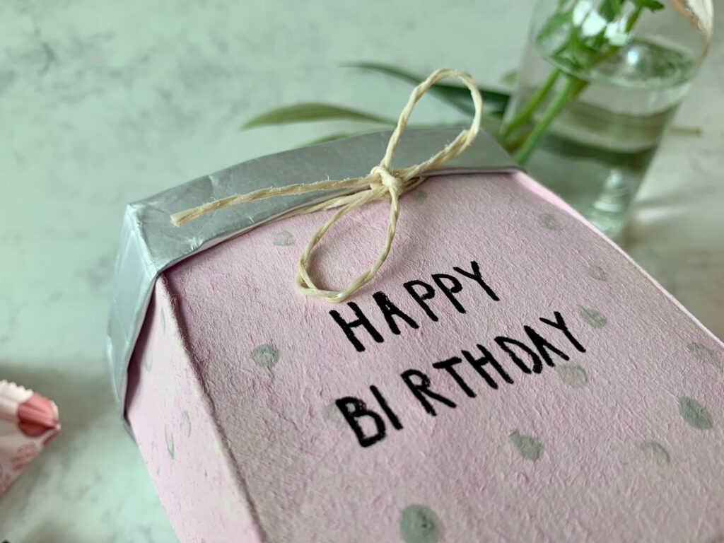 DIY Geschenkidee Geschenkkörbchen aus Milchpackung schräg von oben fotografiert, Bastelidee mit Kleinkind.