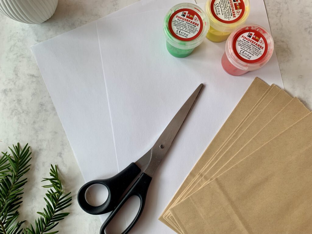Bastelmaterial für DIY Adventskalender mit Kleinkind: Kraftpapiertüten, Fingerfarben und Schere.