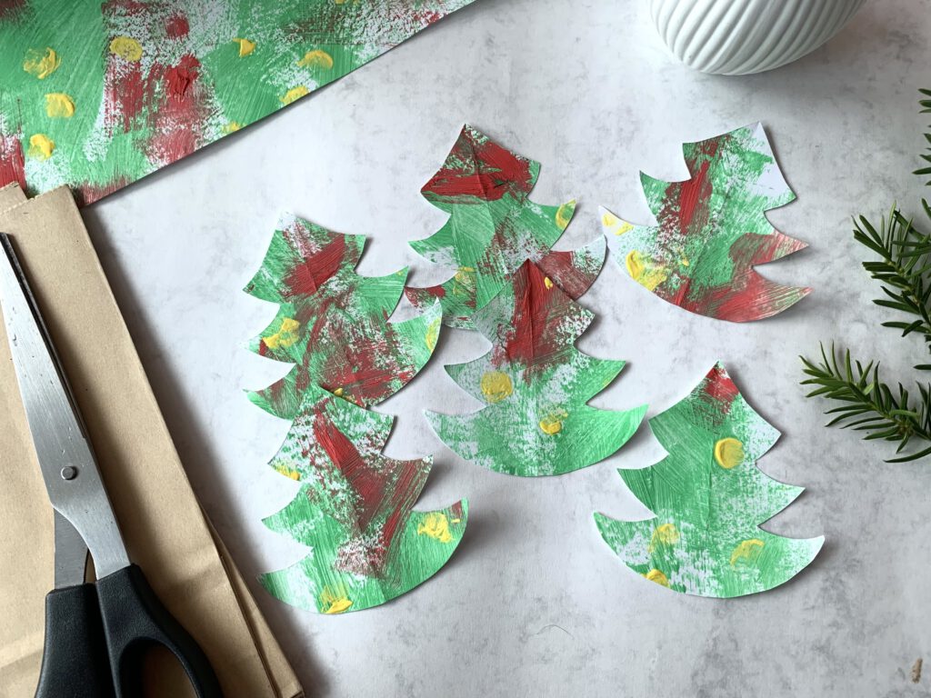 Ausgeschnittene Tannenbäume aus bunten Fingerfarben-Bildern für DIY Adventskalender.