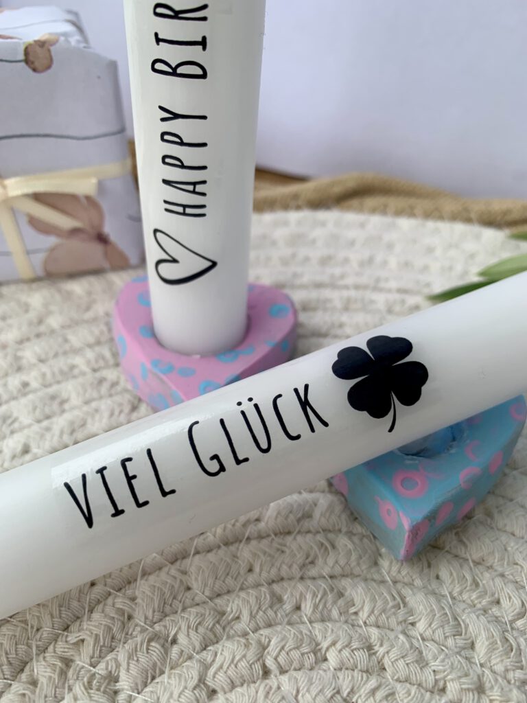 Herzförmige Kerzenhalter aus Modelliermasse in Pastellfarben Rosa und Hellblau mit verzierten Kerzen und Aufschrift ‚Viel Glück‘
