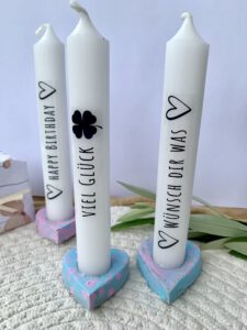 Pastellfarbene Kerzenhalter aus Modelliermasse mit Aufschriften ‚Happy Birthday‘ und ‚Viel Glück‘, ideal als Geschenk von Kindern.