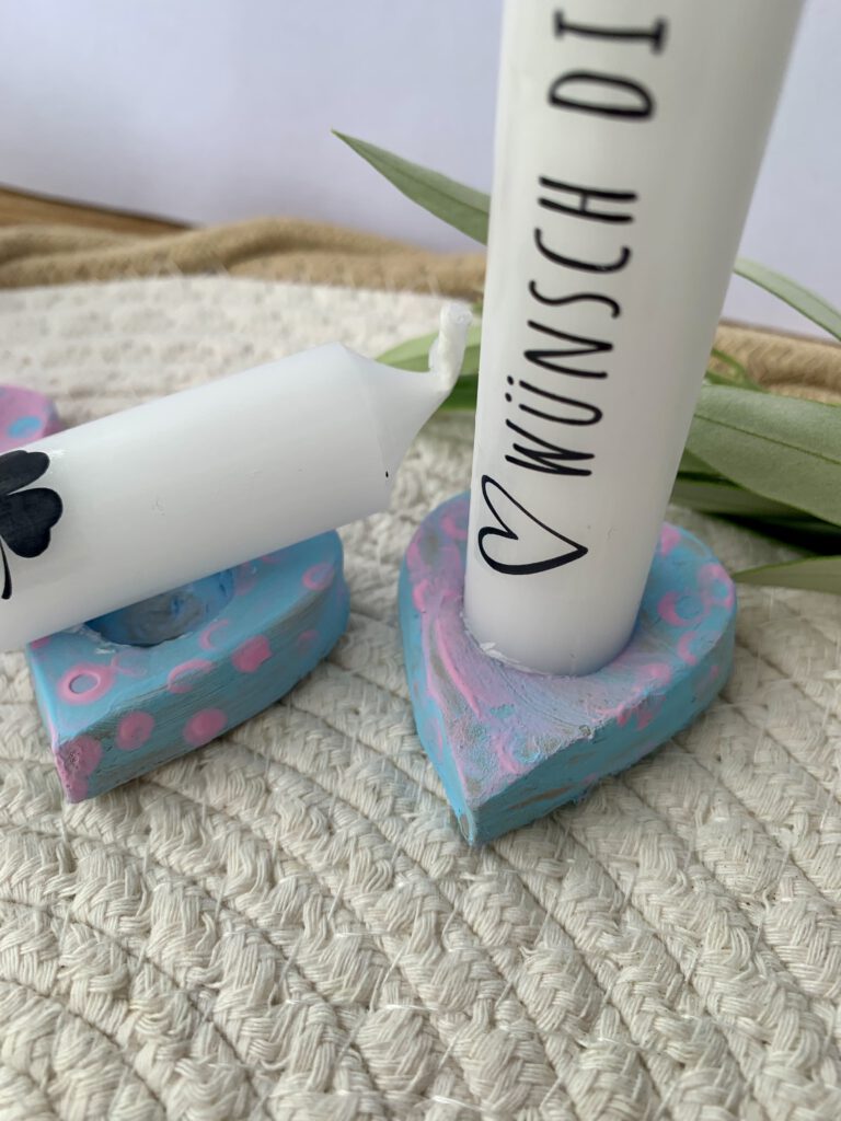 Nahaufnahme von rosa und blauen Kerzenhaltern aus Modelliermasse mit Kerzen und Schriftzug ‚Wünsche dir was‘. Basteln mit Kleinkindern.
