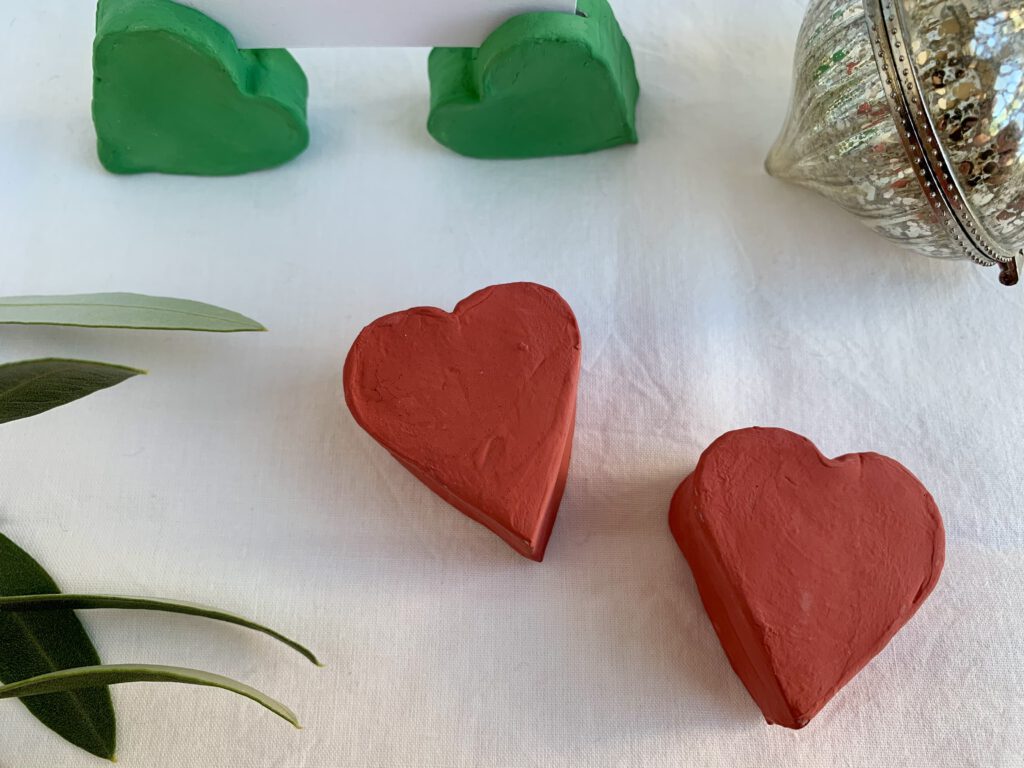 Rote Fotohalter von oben, im Hintergrund grüne Fotohalter mit Weihnachtskarte. Weihnachtsbasteln mit Kleinkind.