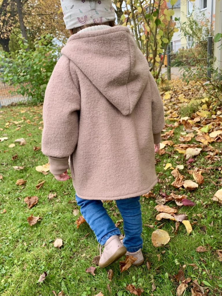 Kleinkind von hinten mit der Wollwalkjacke von Petit Cochon – fair produzierte Kinderjacke aus Bio-Wolle.