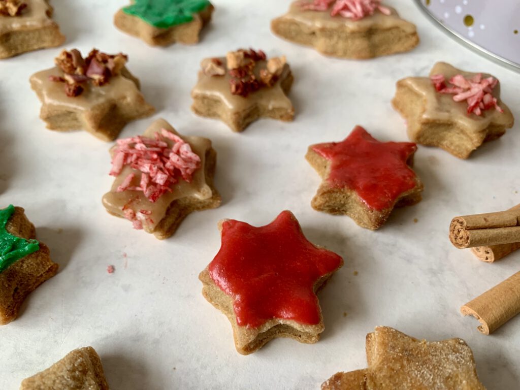Nahaufnahme zuckerfreier Plätzchen mit gefärbtem Mandelmus-Zuckerguss und natürlichem Dekor