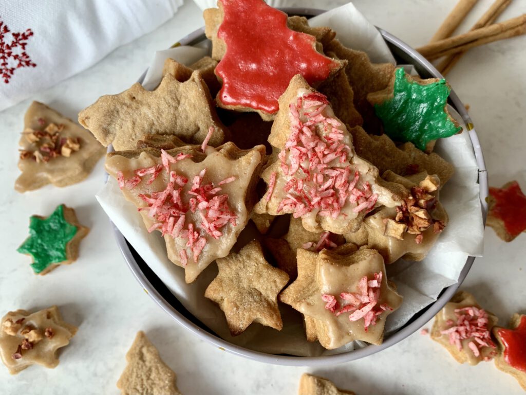 Verschieden verzierte Weihnachtsplätzchen ohne Zucker in einer Dose, perfekt zum gemeinsamen Backen mit Kindern