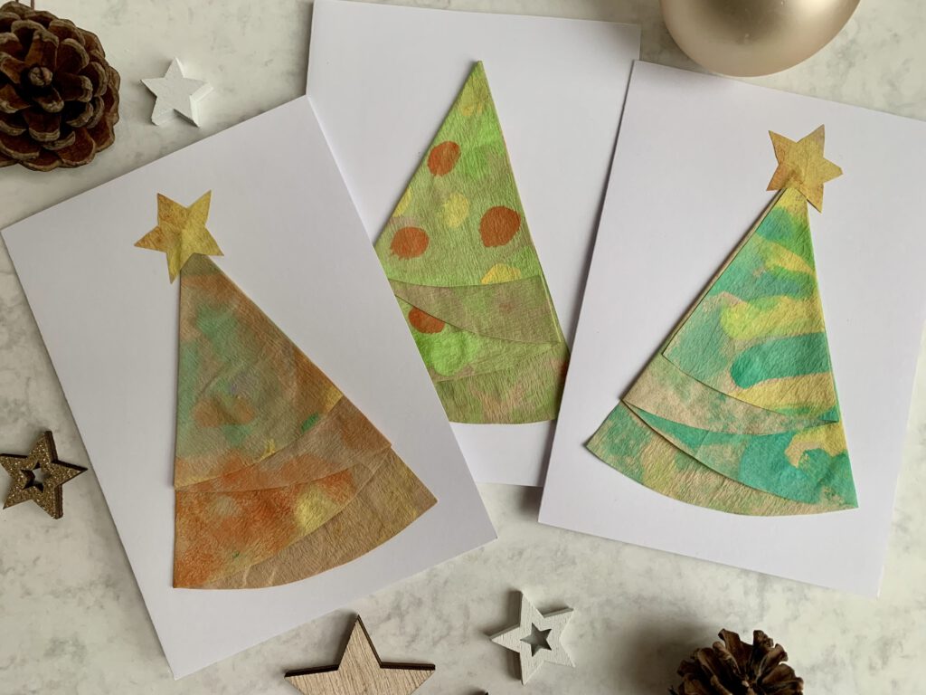 Mehrere liegende Weihnachtskarten mit bunten Tannenbäumen aus Kaffeefiltern und festlicher Deko.