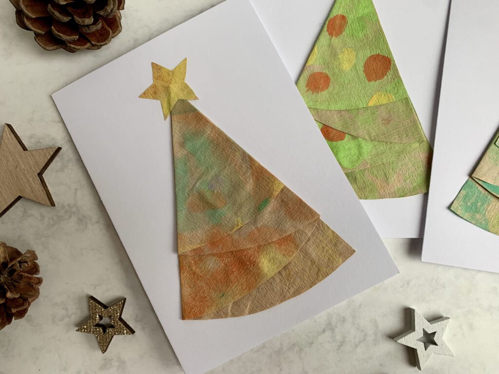Detailfoto einer DIY-Weihnachtskarte mit bemaltem Kaffeefilter-Tannenbaum auf weißer Karte.
