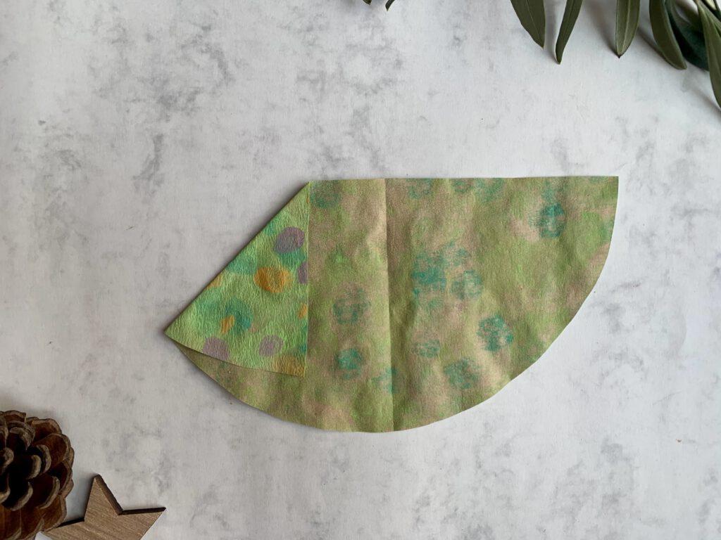 Halbkreis aus Kaffeefilter wird fächerartig gefaltet – erste Ecke des Tannenbaums umgelegt. Schritt für Schritt Anleitung: Tannenbaum falten aus Halbkreis für selbstgemachte Weihnachtskarten