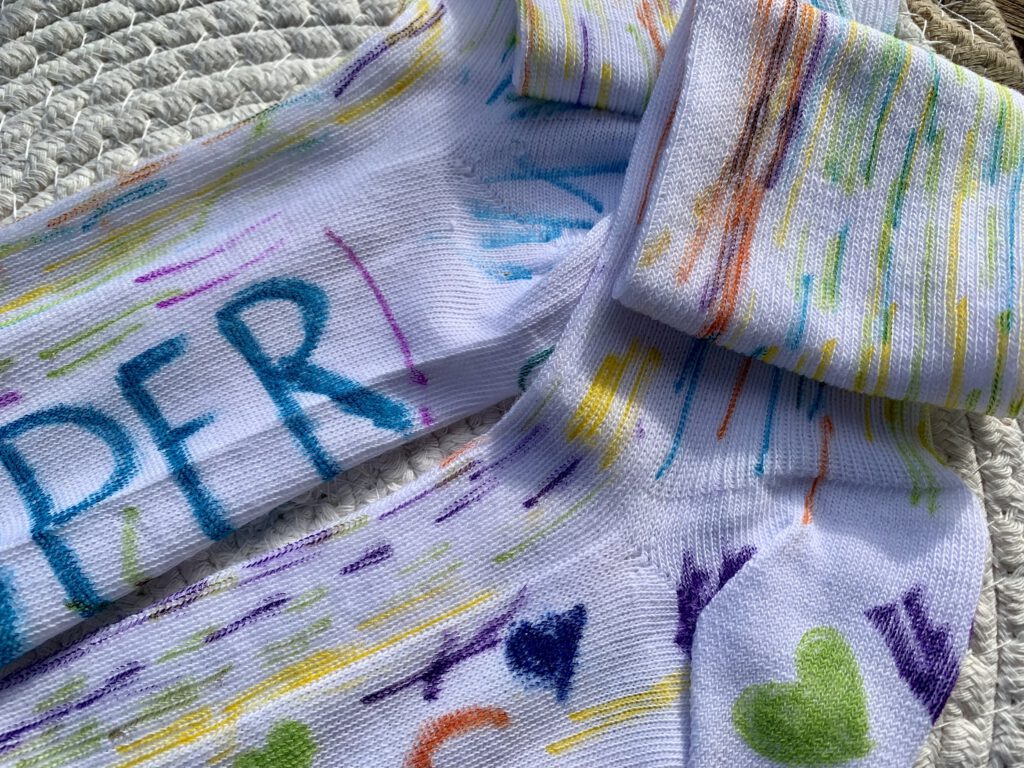Nahaufnahme bemalter Socken mit bunten Linien und Punkten – einfache Bastelidee mit Kindern ab 2 Jahren.