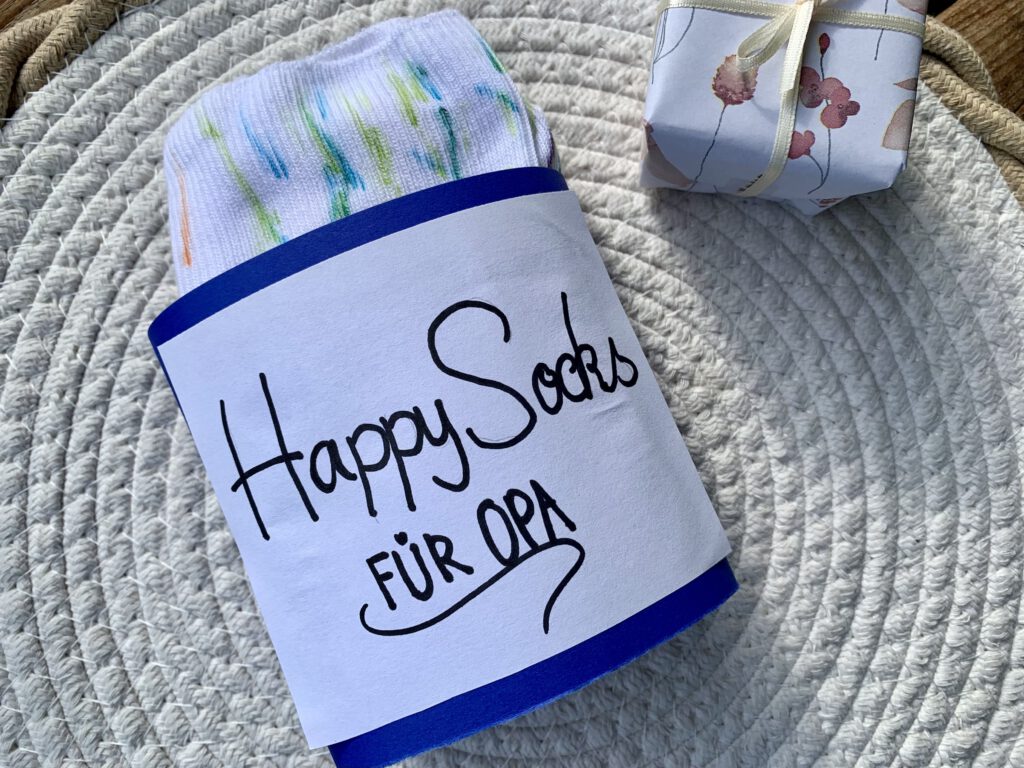 DIY-Geschenkverpackung Happy Socks für Opa mit bemalten Socken – kreative Bastelidee mit Kleinkindern.
