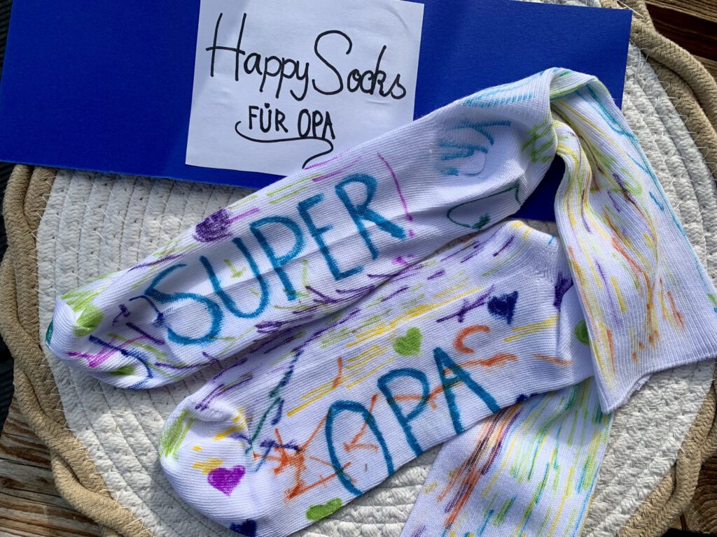 Bunte DIY-Socken mit der Aufschrift Super-Opa und Geschenkbanderole Happy Socks für Opa – kreative Geschenkidee mit Kindern.