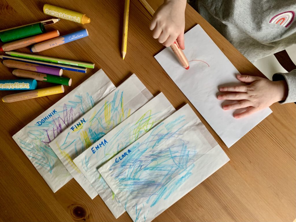 Kleinkind bemalt Papiertüten für die Mitbringseltüten