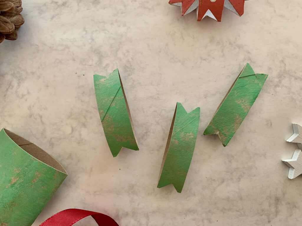 Klorollen-Streifen mit ausgeschnittenen Ecken als Vorbereitung für einen Weihnachtsstern, Bastelidee mit Kleinkindern.