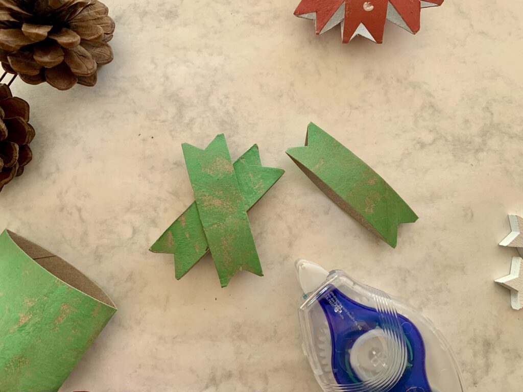 Bastelschritt: Aus bemalten Klorollen-Streifen wird ein Weihnachtsstern mit einer Klebemaus zusammengeklebt.