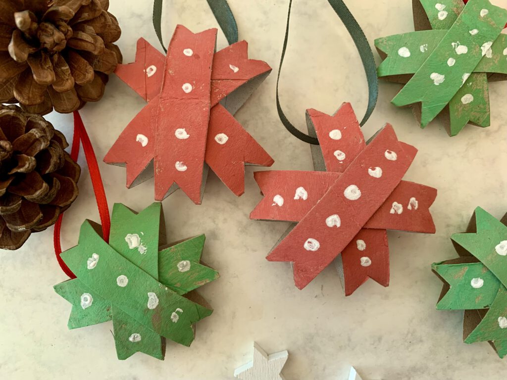 Fertige Weihnachtssterne in Rot und Grün aus Toilettenpapierrollen, nachhaltige Bastelidee zu Weihnachten.