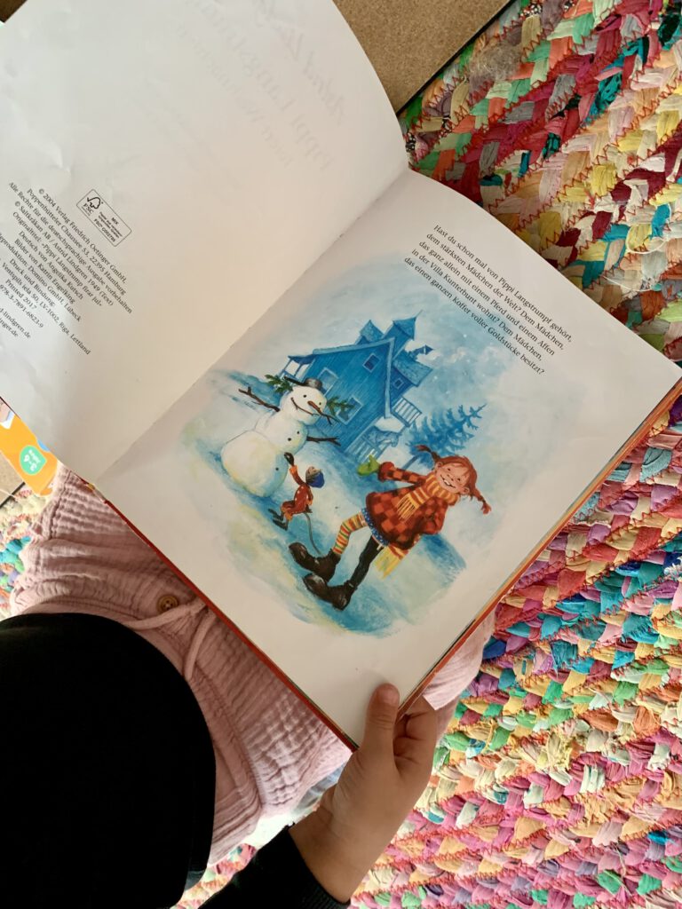 Kleinkind schaut das Weihnachtsbuch Pippi Langstrumpf feiert Weihnachten an