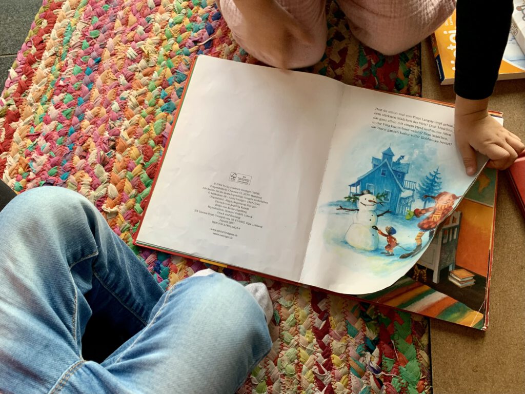 Zwei Kinder blättern gemeinsam im Weihnachtsbuch Pippi Langstrumpf feiert Weihnachten