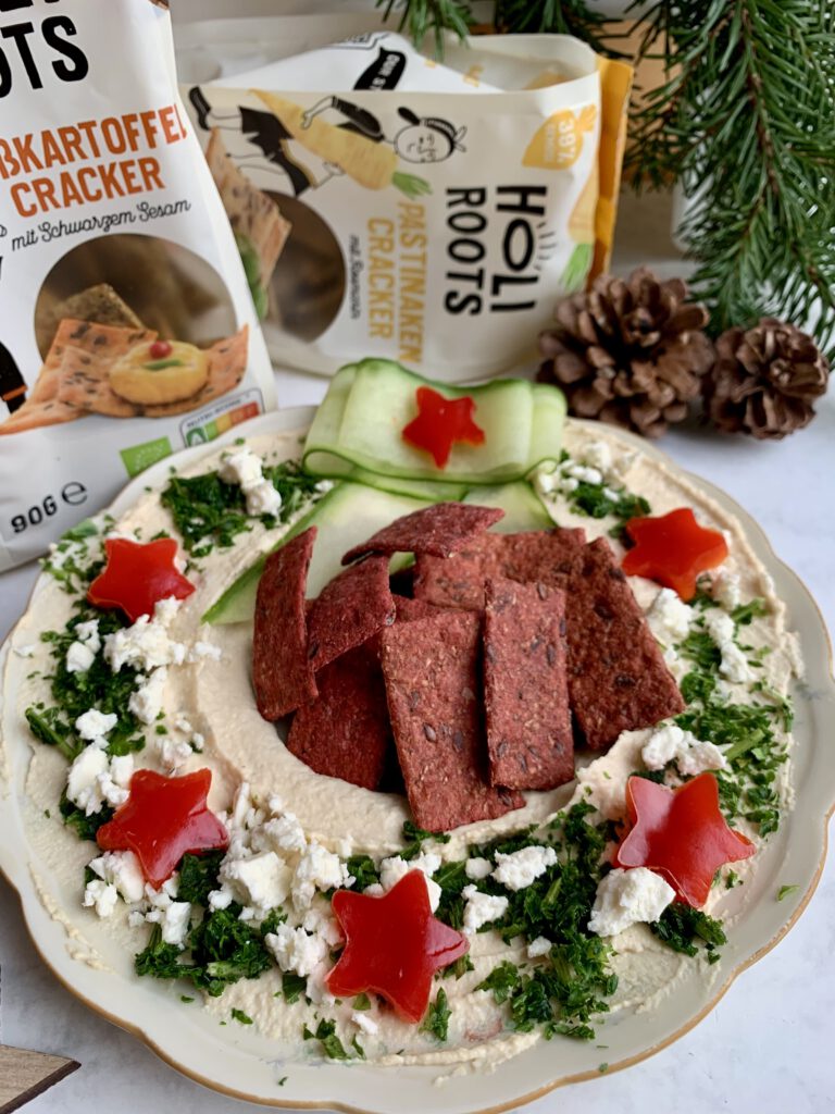 weihnachtliche-snacks-holiroots-cracker-platte.jpg Herzhafte weihnachtliche Snackplatte mit verschiedenen Holiroots Gemüsecrackern. Hummus Dip dekoriert als Kranz - ein leckeres Rezept für Weihnachten mit Gästen.