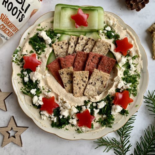 Hummus-Kranz mit Holiroots Crackern in den Sorten Rote Bete und Pastinake als herzhafter Weihnachtssnack für Gäste.