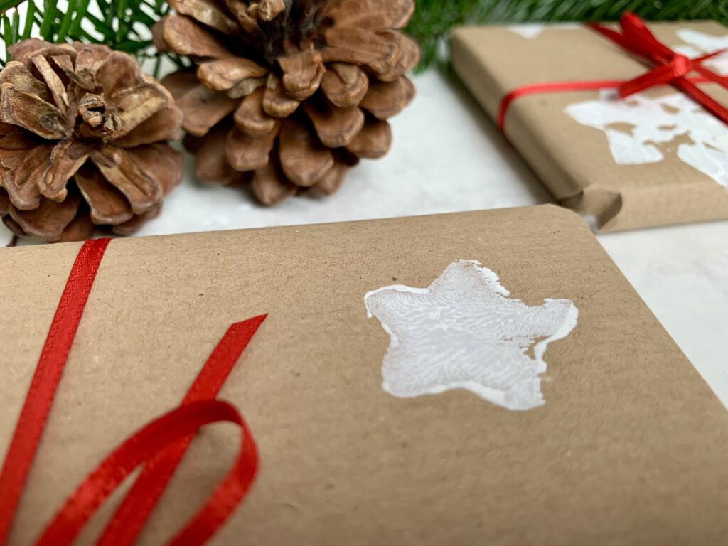 Nahaufnahme eines gestempelten Sterns auf selbstgemachtem Geschenkpapier – kreative Weihnachtsidee