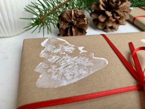 Detailbild eines Geschenks mit gestempeltem Tannenbaum auf Packpapier – weihnachtliches Geschenkpapier selber machen
