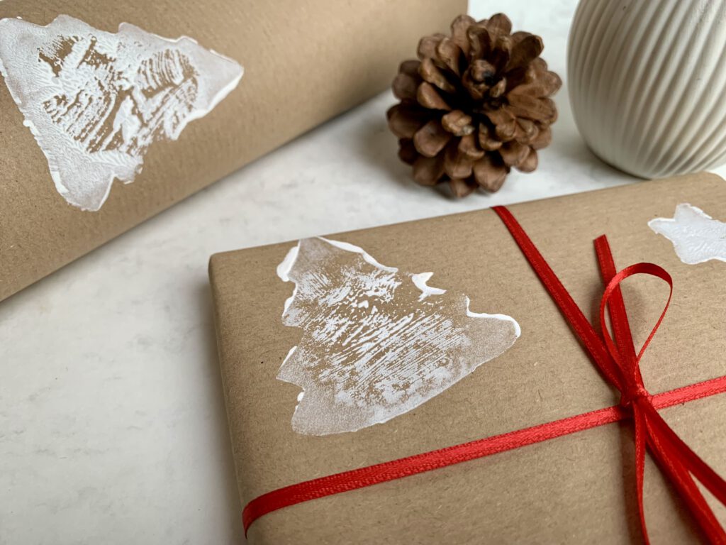 Detailaufnahme eines Tannenbaums auf eingepacktem Geschenk – Stempelidee für weihnachtliches Geschenkpapier