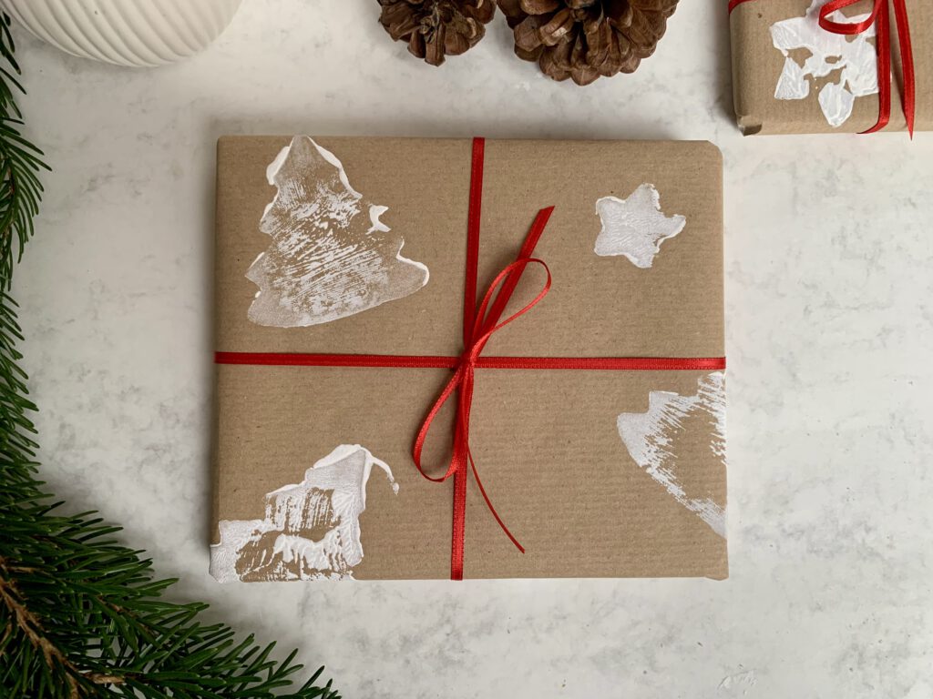 Geschenk in selbstgemachtem Papier mit roter Schleife – liebevoll verpackte DIY-Idee