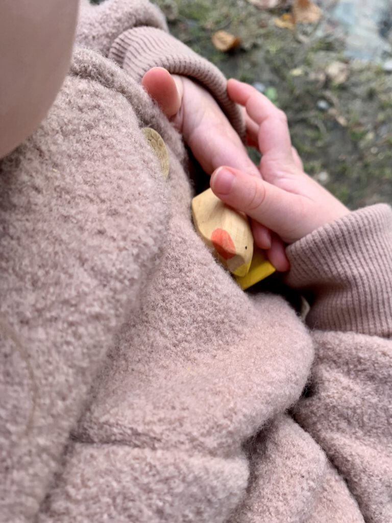 Kleinkind drückt ein Sägefisch-Holzhuhn an sich – hochwertige Holzfigur aus deutscher Handarbeit.