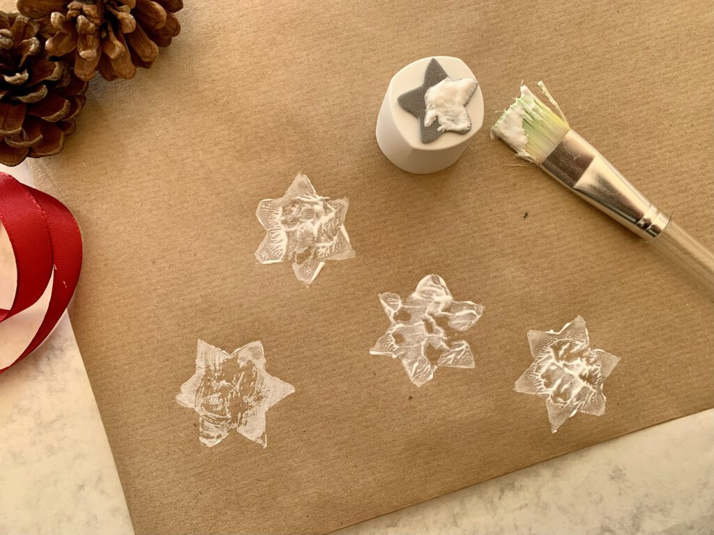 Sternenstempel mit Pinsel und weiße Sterne auf Packpapier gestempelt – einfache Bastelidee mit Kindern